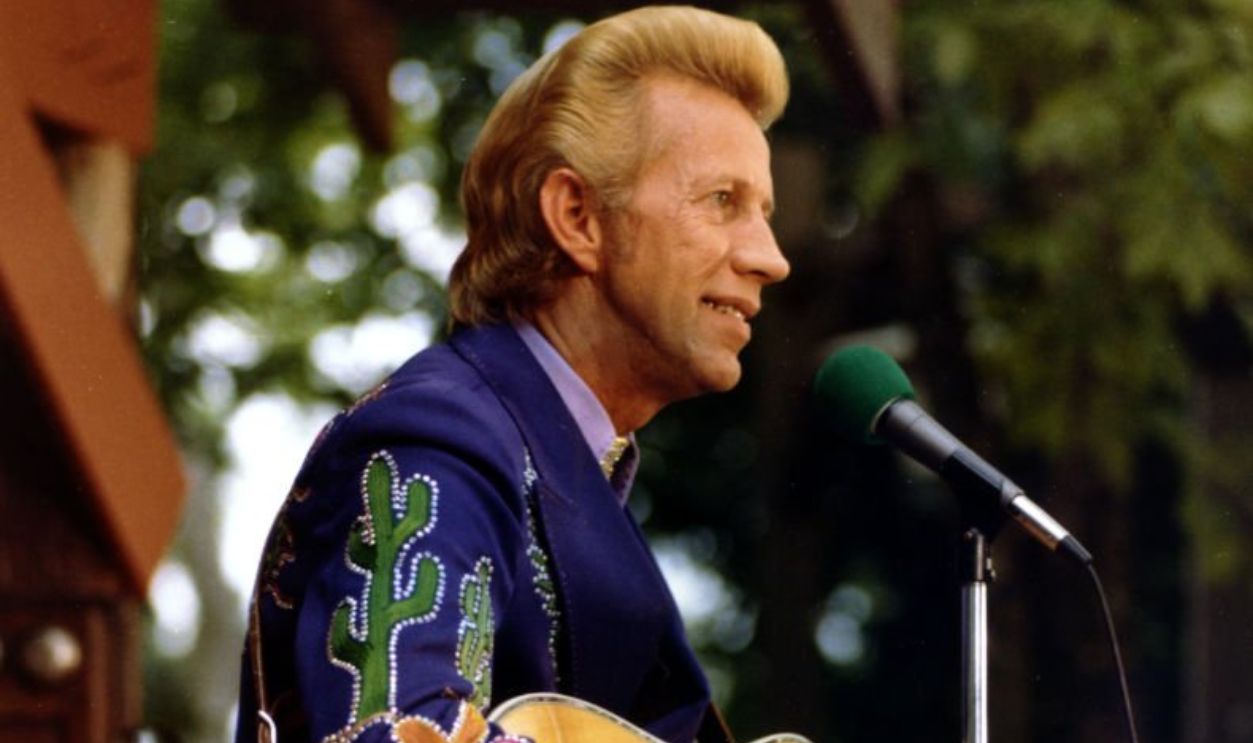 CIRCA 1973: Country singer Porter Wagoner performs onstage with an acoustic guitar in circa 1973. Mr. Wagoner is wearing a Nudie Suit designed by Nudie Cohn of Nudie's Rodeo Tailors. 