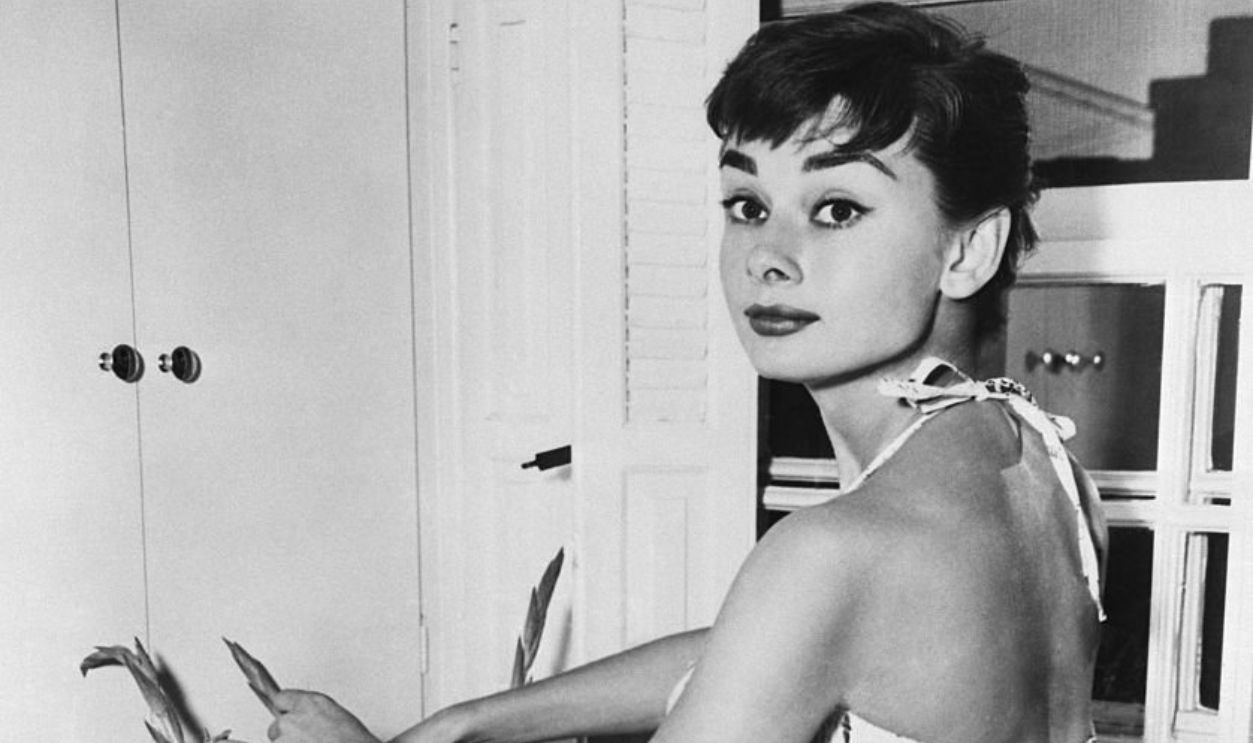 (Original Caption) 6/30/1954-New York, NY: Pixyish Audrey Hepburn, Academy Award actress, beats the Manhattan heat with a cool play suit as she does chores in her New York apartment. Miss Hepburn, who will soon be seen in the movie 