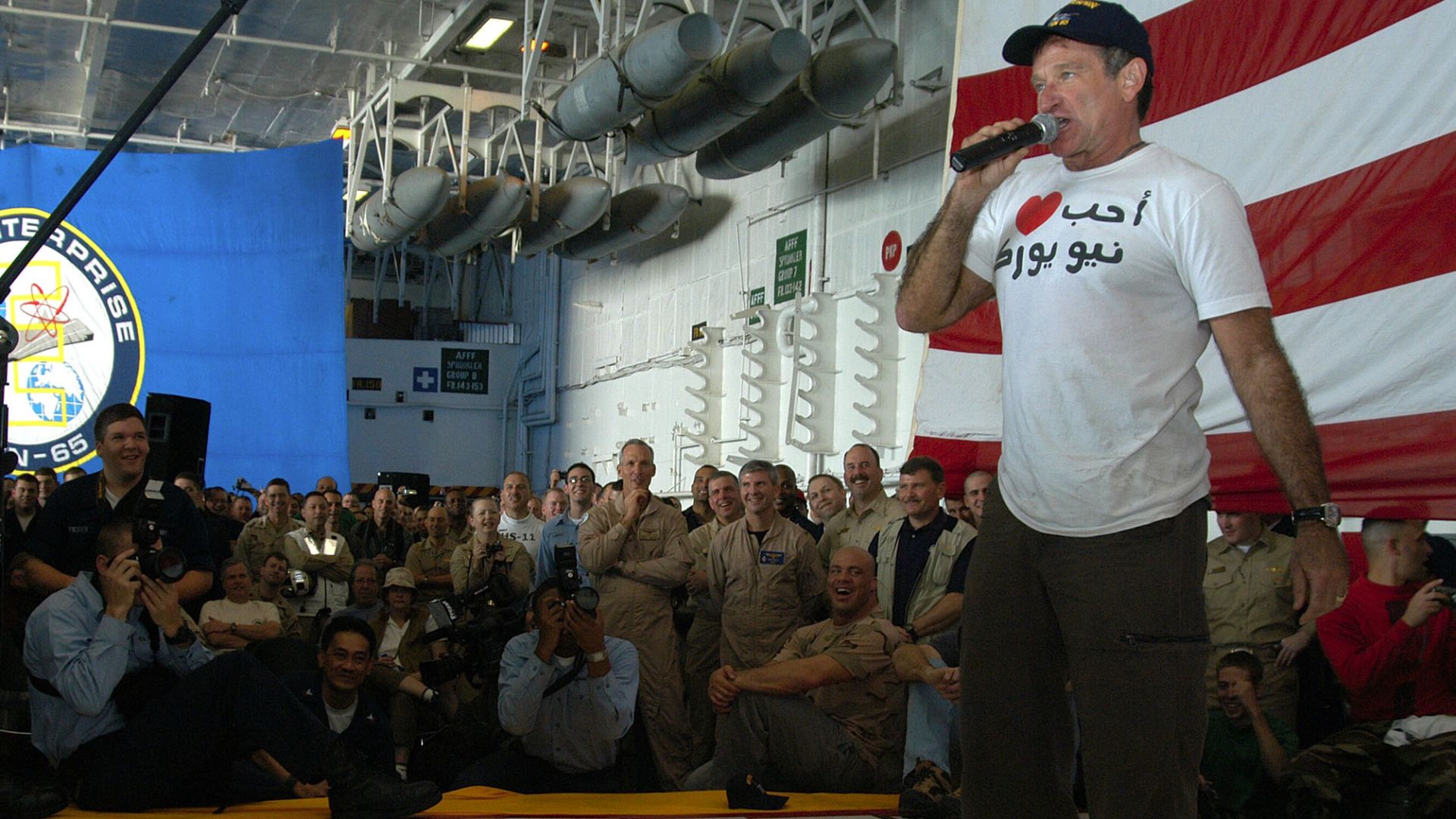 Actor/comedian Robin Williams entertains the crew of USS Enterprise (CVN 65) during a holiday special hosted by the United Service Organization (USO). The show took place in the ship's hangar bay and featured the visiting Chairman of the Joint Chiefs of S