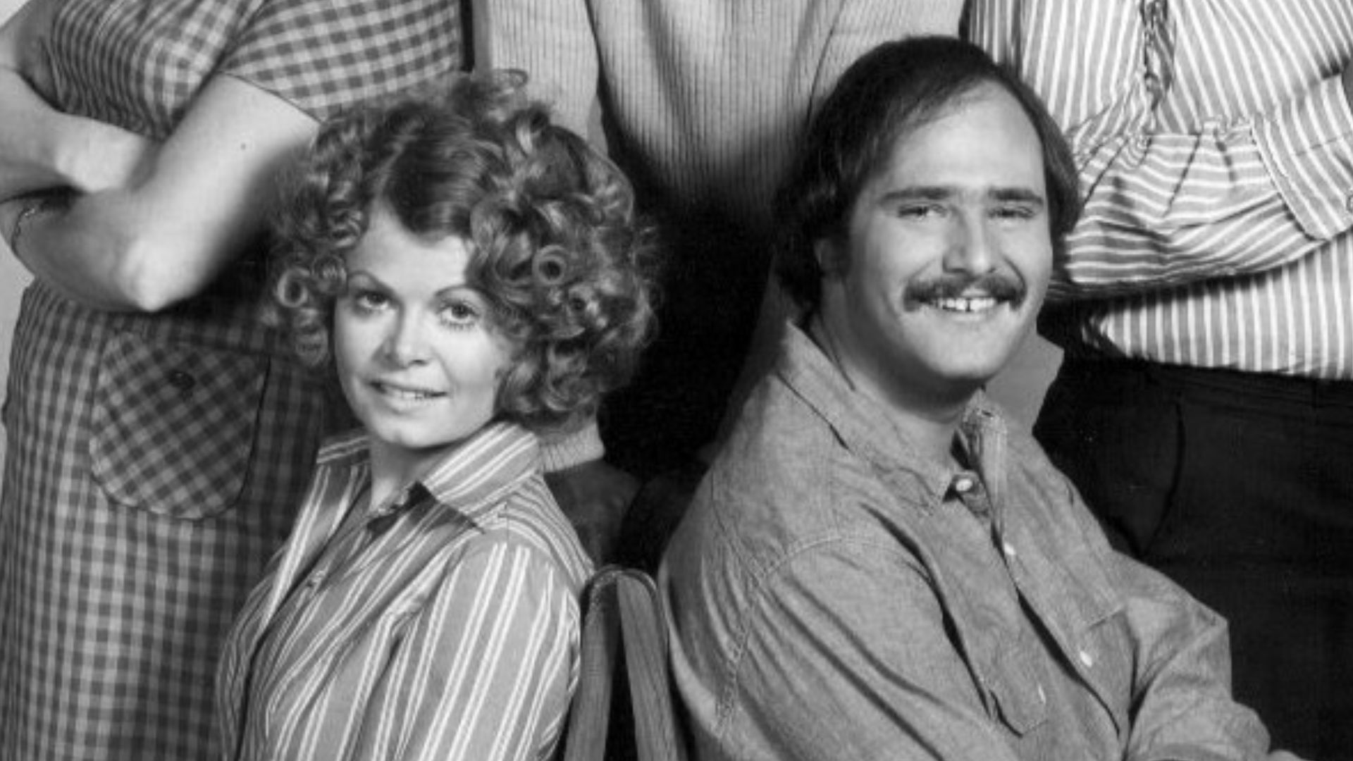Photo of the cast of the television program All In the Family.  Standing, from left: Jean Stapleton (Edith Bunker), Mike Evans (Lionel Jefferson), Carroll O'Connor (Archie Bunker).  Seated: Sally Struthers (Gloria Bunker Stivic) and Rob Reiner (Mike Stivi