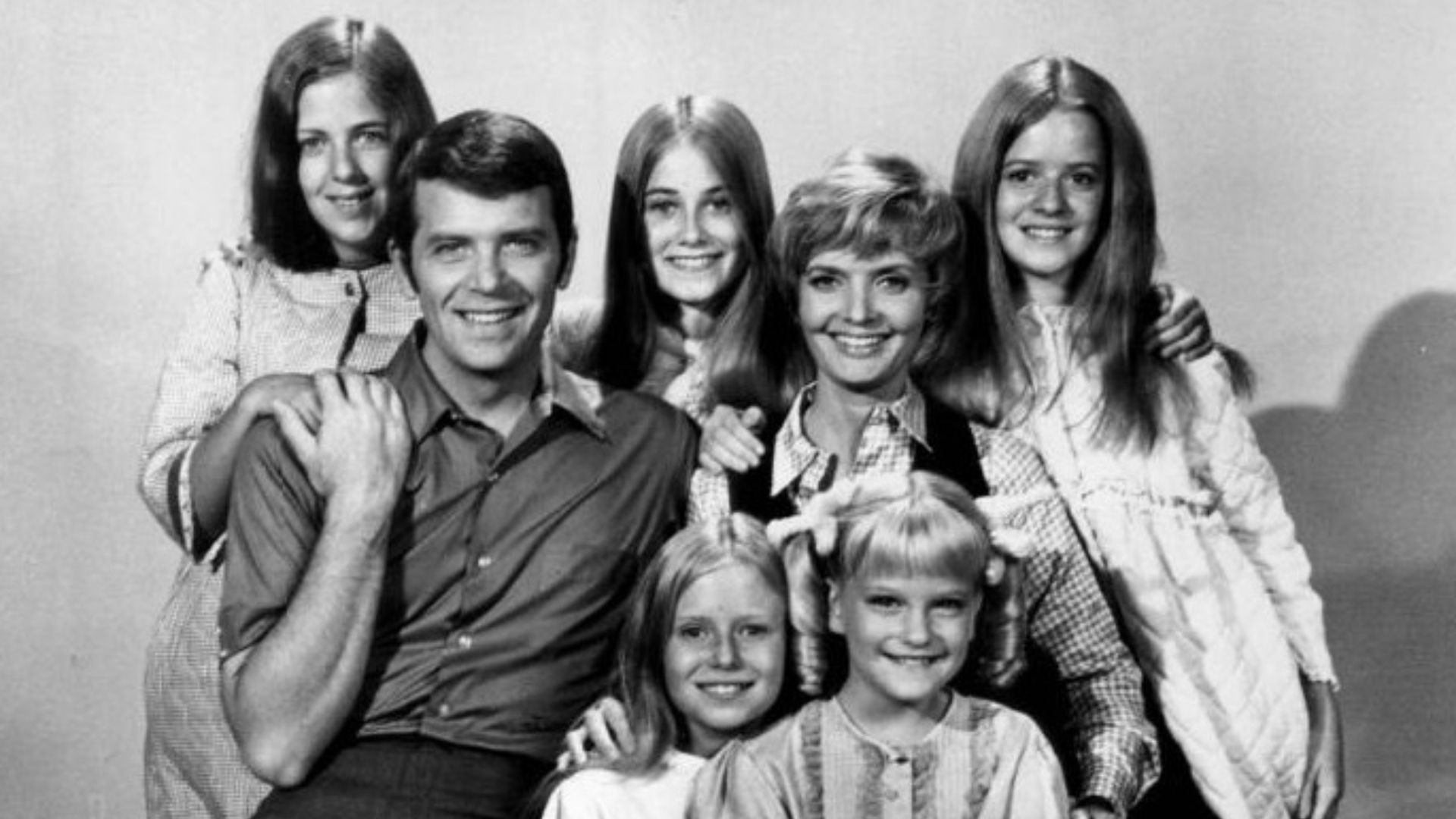Publicity photo of American actors, (front row; sitting; L–R) Eve Plumb, Susan Olsen, (second row; sitting; L–R) Robert Reed, Florence Henderson, (back row; standing; L-R) Carolyn Reed, Maureen McCormick and Barbara Henderson Bernstein promoting the Octob
