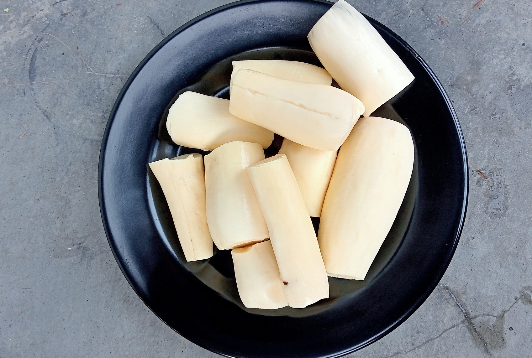 Cassava that has been peeled and served on a black plate.