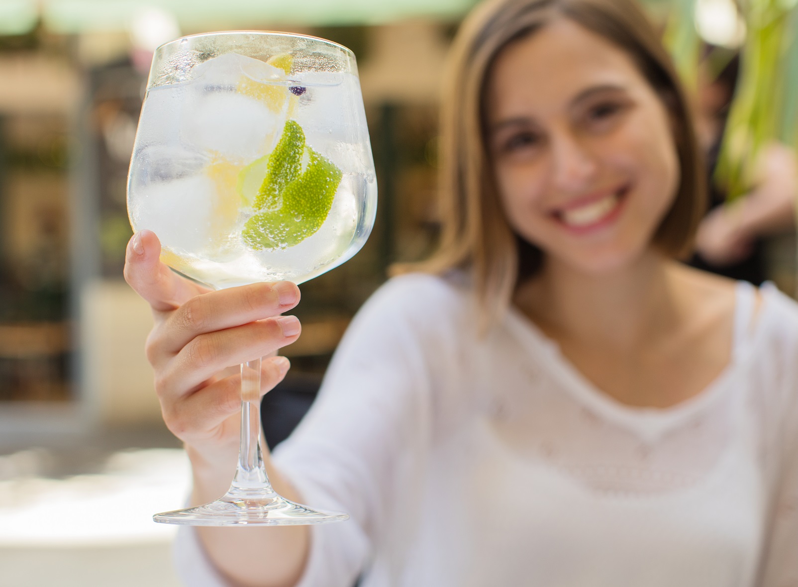 Young woman in a restaurant with gin tonic at her hand.