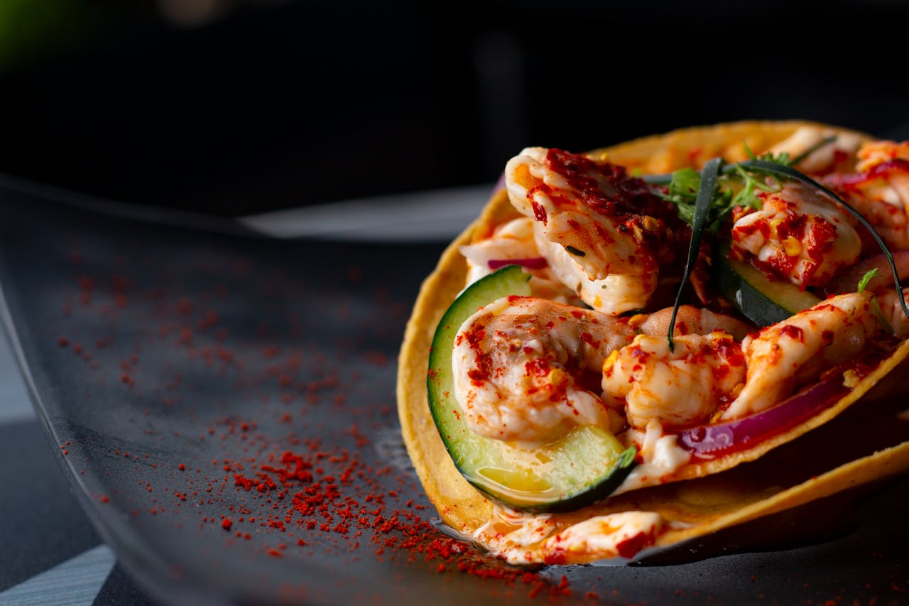 Close-up Photo of Spicy Shrimps and Vegetable in a Taco Shell in a dark plate