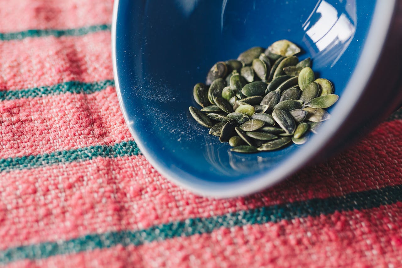 Close-up Photo of Green Pumpkin Seeds In Blue Bowl