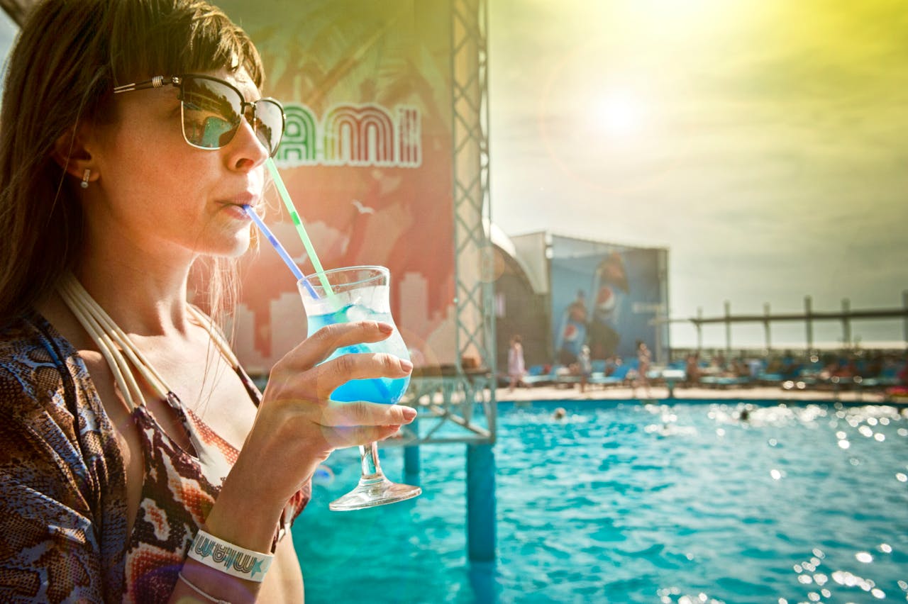 Woman drinking Blue cocktail Beside In-ground Pool