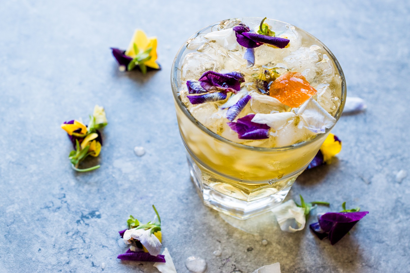 Herbal Iced Tea Cocktail with Edible Flowers and Crushed Ice.
