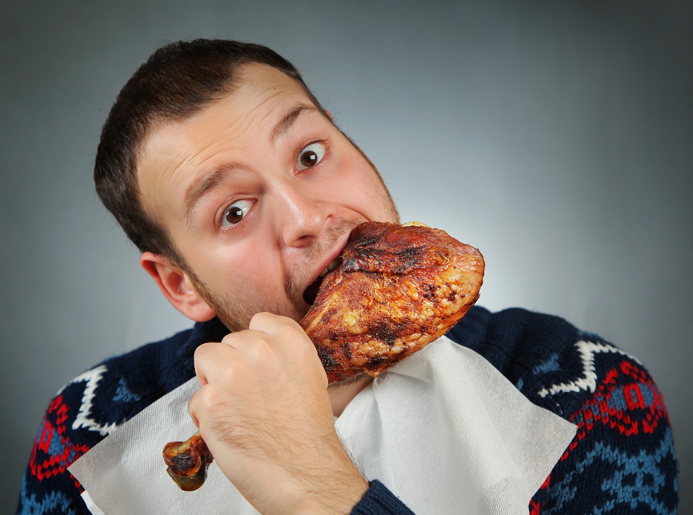 happy young man eating chicken meat