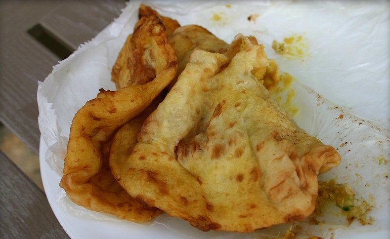 Close-up Photo of Doubles on a white plate placed on a wooden table