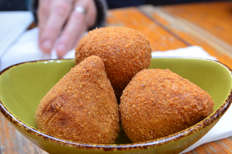 Close-up Photo of Coxinhas on a green bowl placed on a wooden table, blurred background