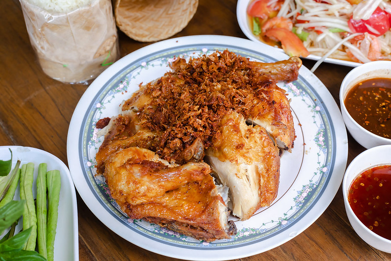 Close-up Photo of thai fried chicken in a white plate placed on a wooden table