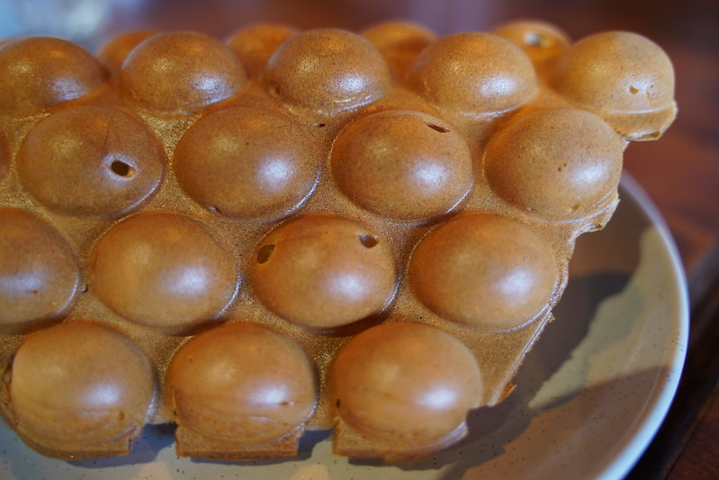 Close-up Photo of Egg waffle on a white plate placed on a wooden table