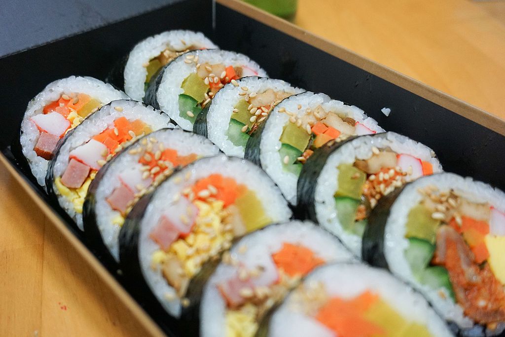 Close-up photo of Vegetable Gimbap on a wooden plate, placed on a wooden table