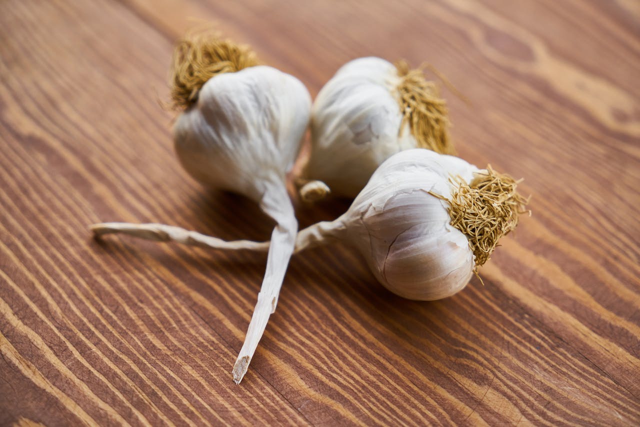 Photo of Three Garlic on Wooden Surface