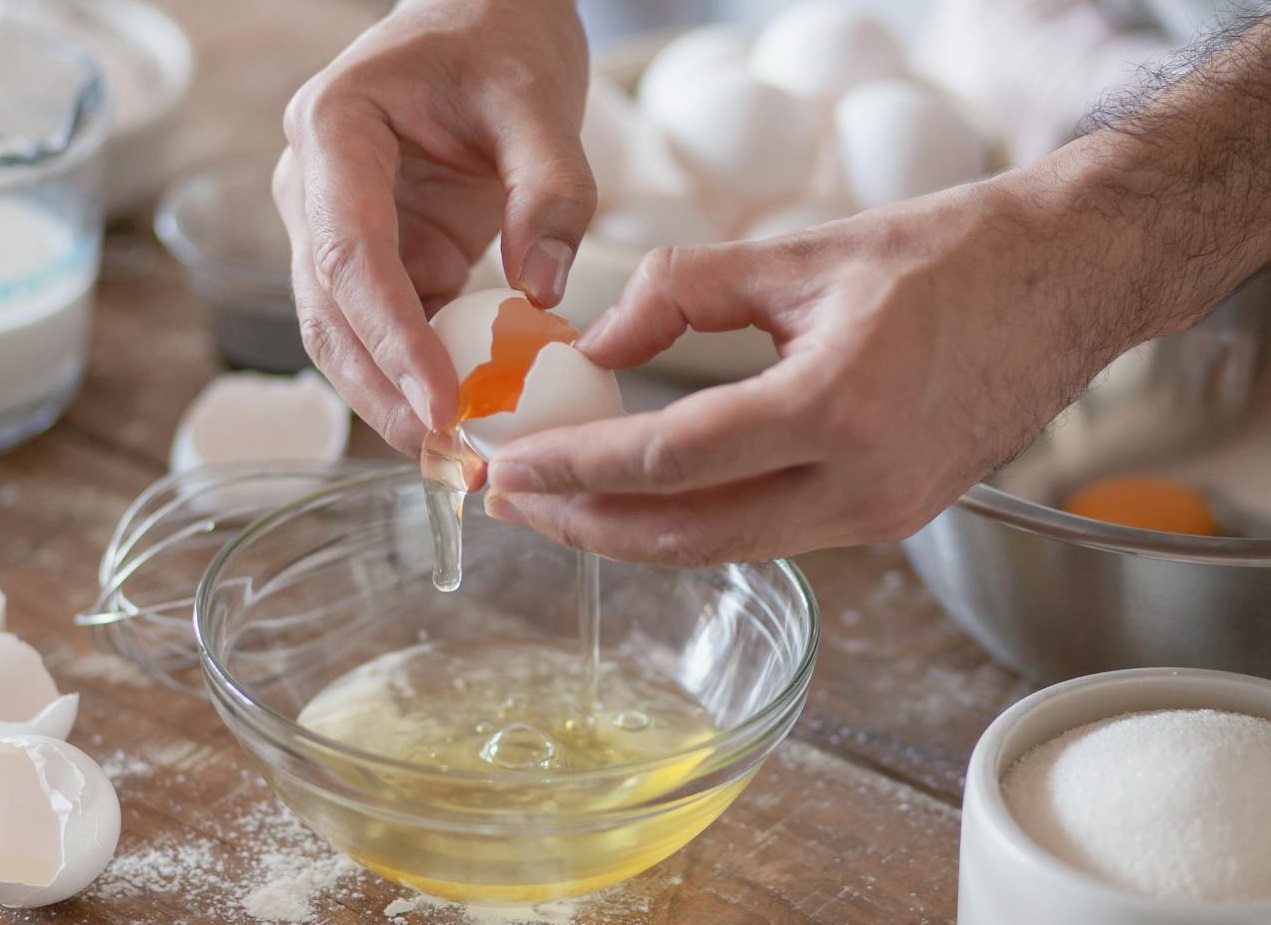 Person Cracking an Egg on a Glass Bowl