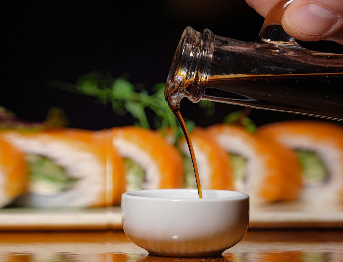 Photo of a Hand Pouring Soy Sauce into a Bowl