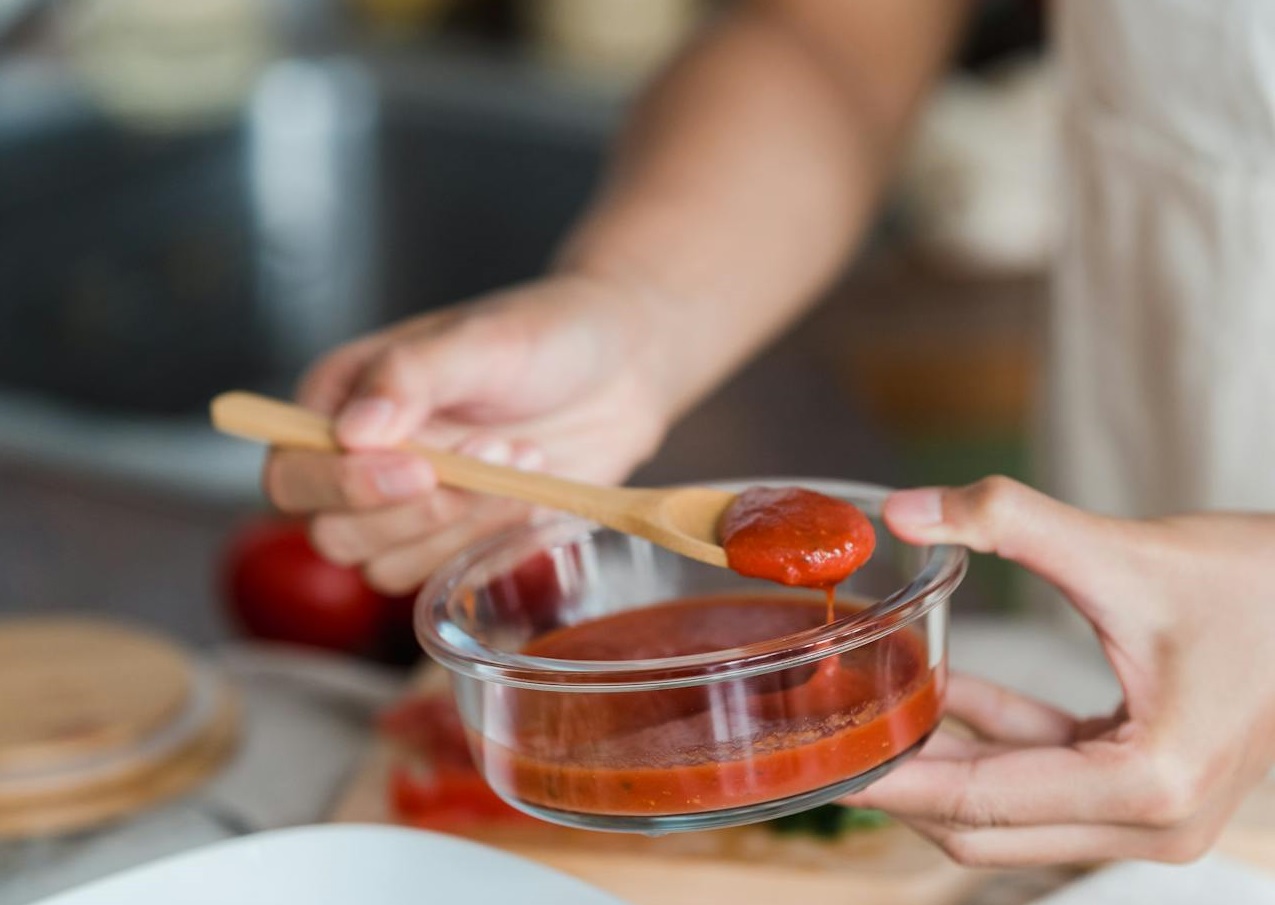 A Person Putting Tomato Sauce