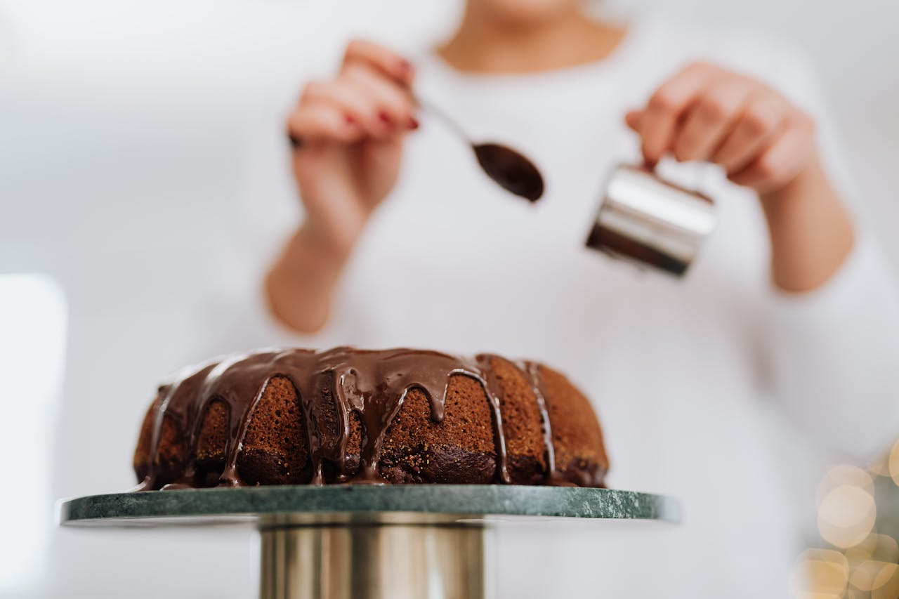 A Person Putting Chocolate Icing on a Chocolate Cake