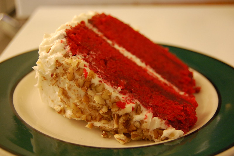 Close-up Photo of a Slice of Red Velvet Cake in a green plate placed on a wooden table