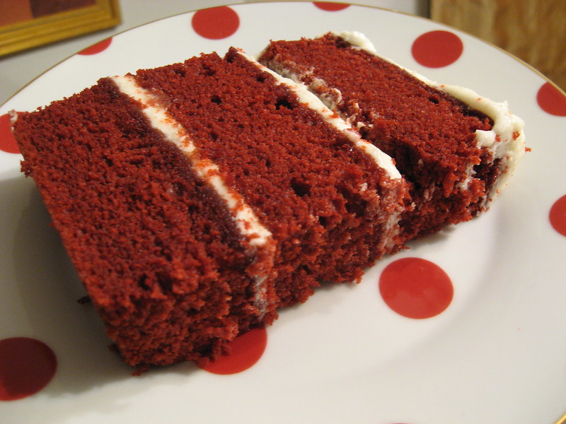 Close-up Photo of a Slice of Red Velvet Cake in a white plate placed on a wooden table