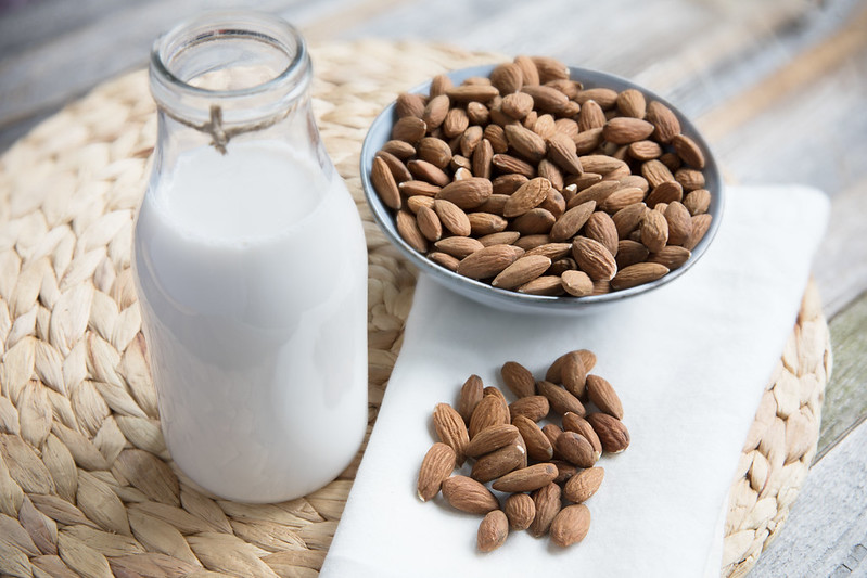 Close-up Photo of Almond Milk bottle and almond placed on a wooden surface