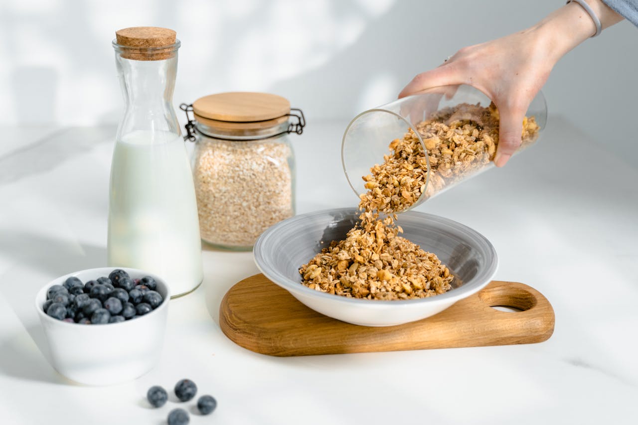 Photo of a persons hand Pouring Granola in a Bowl