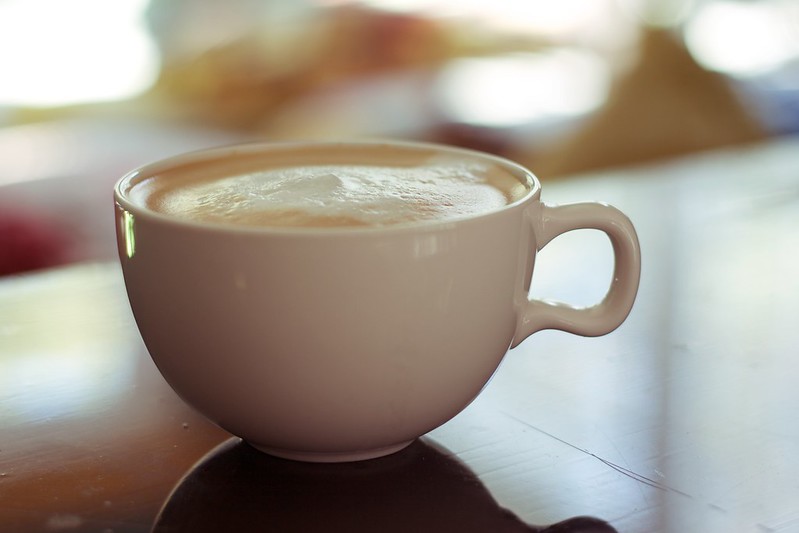 Close Up Photo of a cup of coffee with milk foam placed on a wooden table