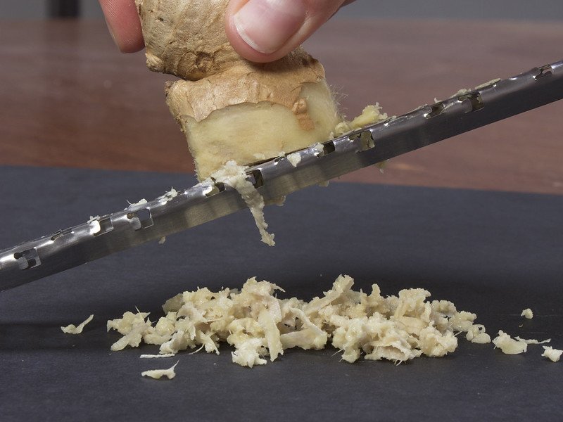 Close Up Photo of Person Grating Ginger with Microplane