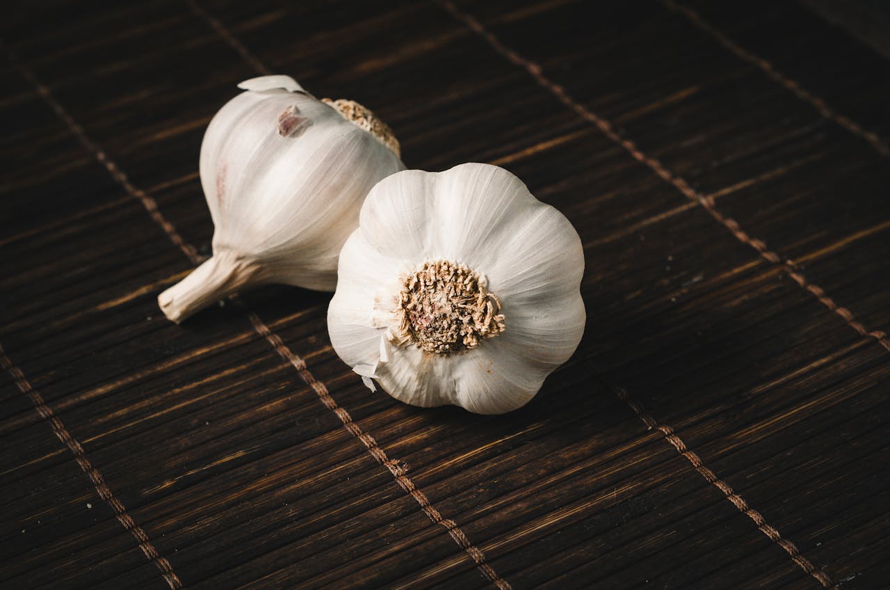Close Up Photo of Two White Garlics placed on a wooden surface