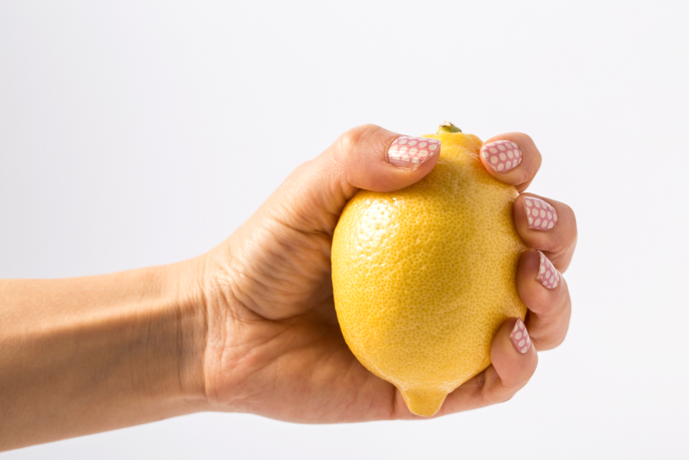 Close Up Photo of hand squeezing whole lemon