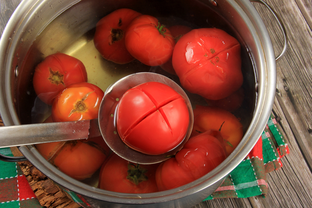 Red ripe tomatoes in a pot of hot water.