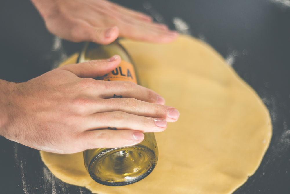 Close Up Photo of Man rolling dough with the bottle
