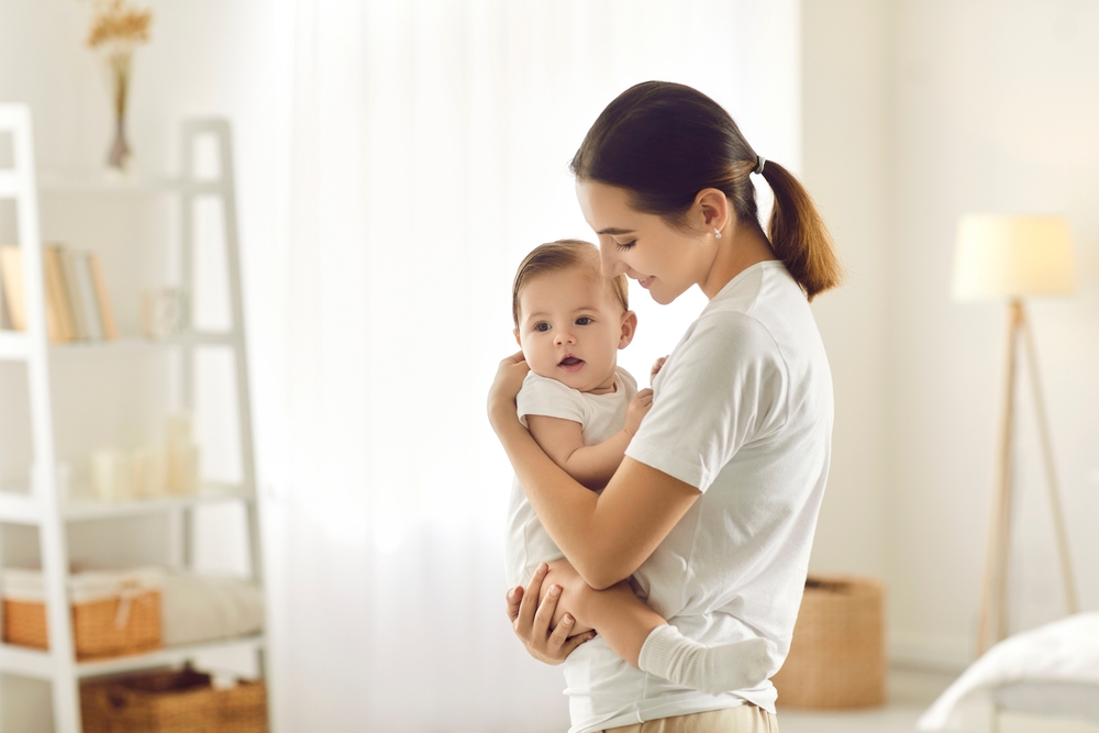 mom standing in bedroom holding her baby