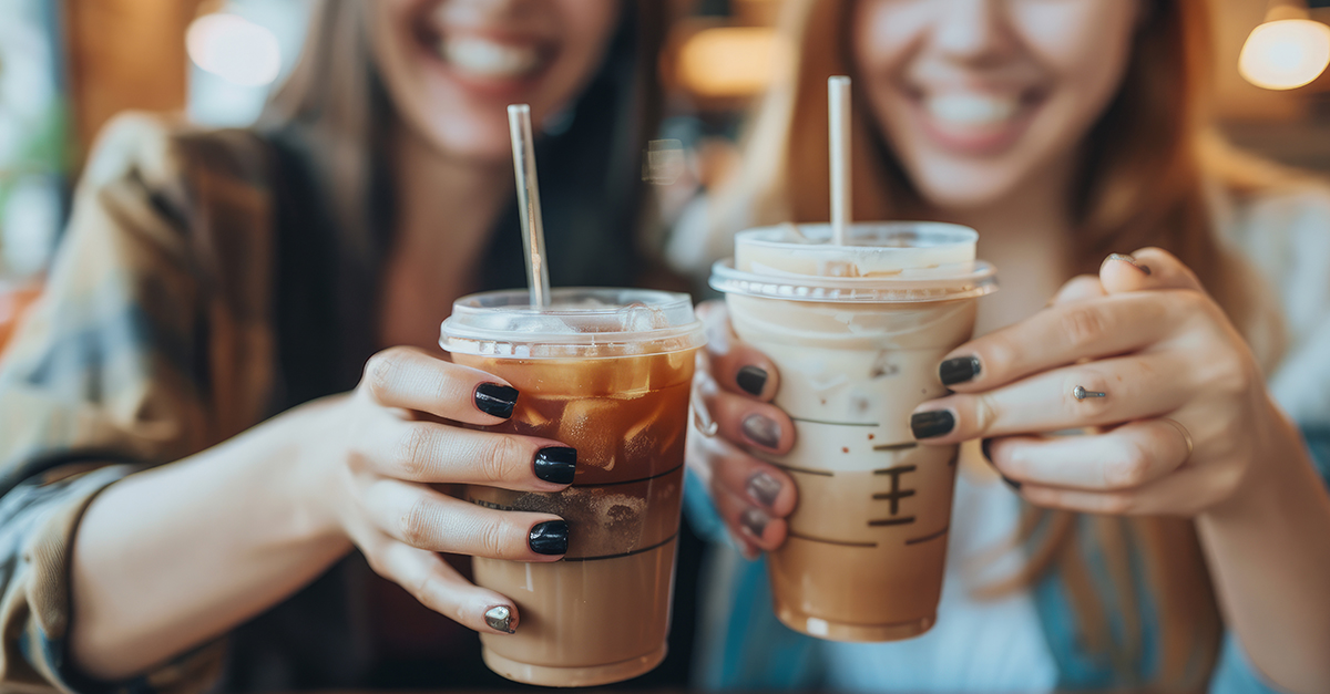 Girls having good time,cheering and drinking cold drinks, enjoying friendship together in coffee shop, close up view on hands