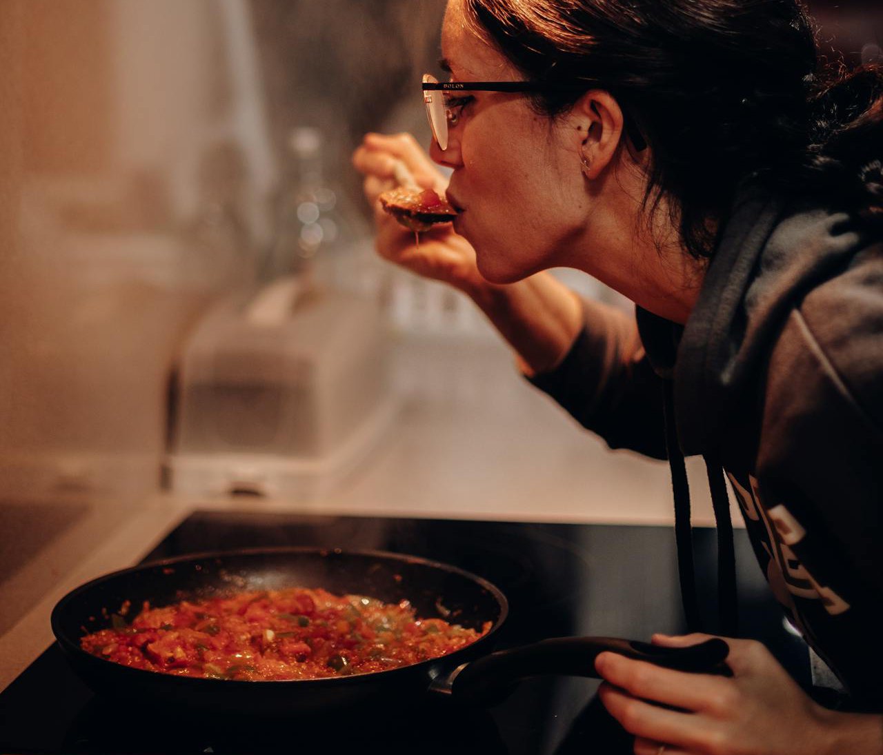 Woman Tasting Food over a Cooking Pan