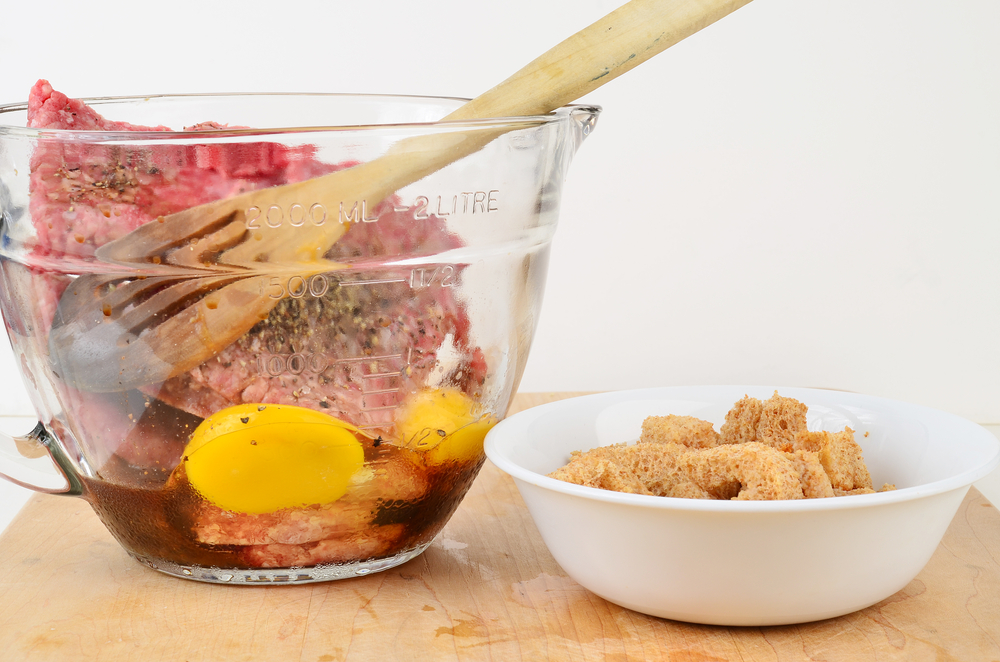 Making meatloaf with raw eggs and seasoning in clear glass