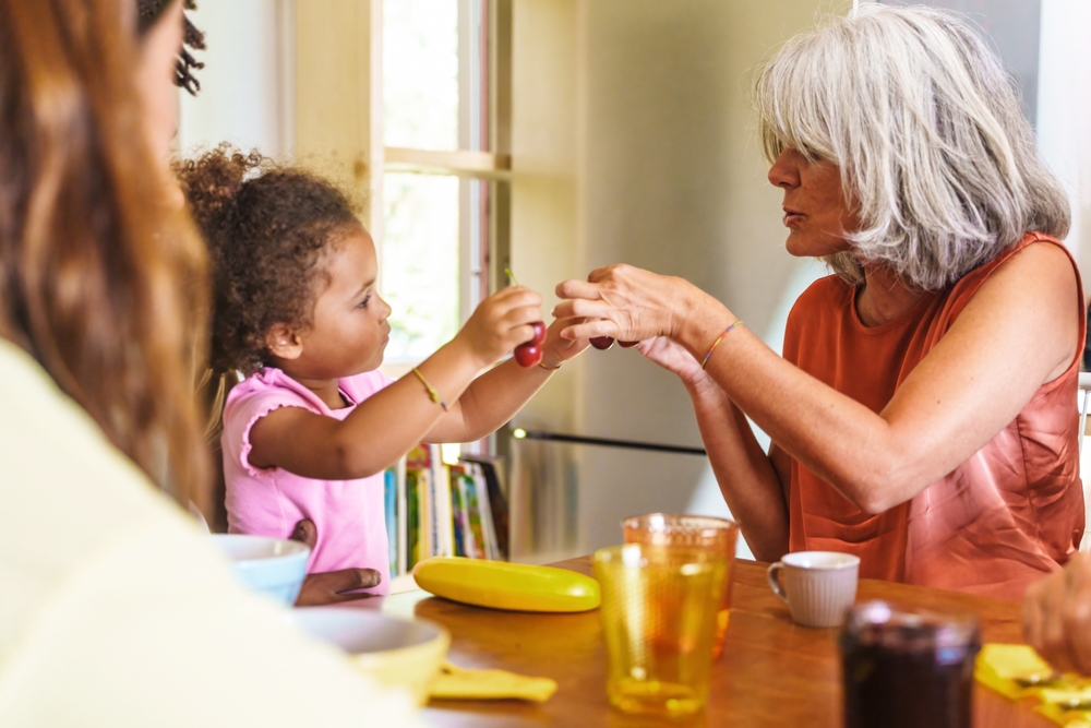 Toddler engages with their grandparent over breakfast