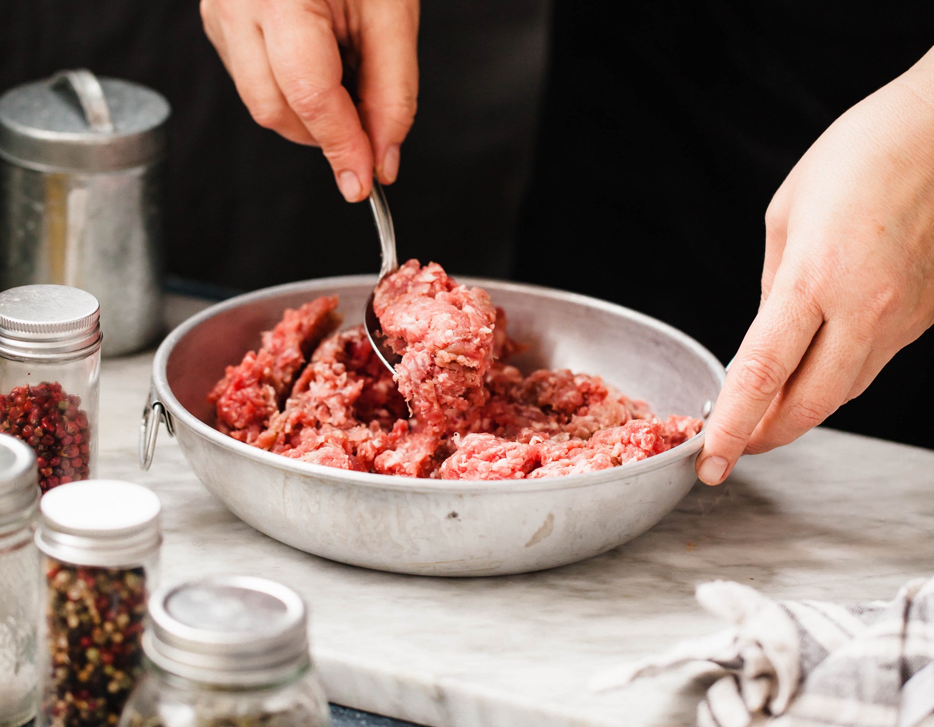 Beef Minced meat bowl. Female hand mixing beef minced meat in bowl on marble board.
