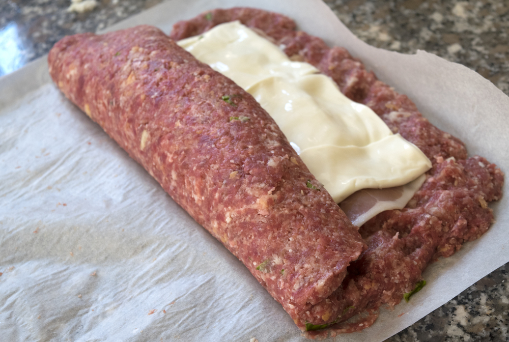 making beef meatloaf with filling of cheese cured ham and omelette
