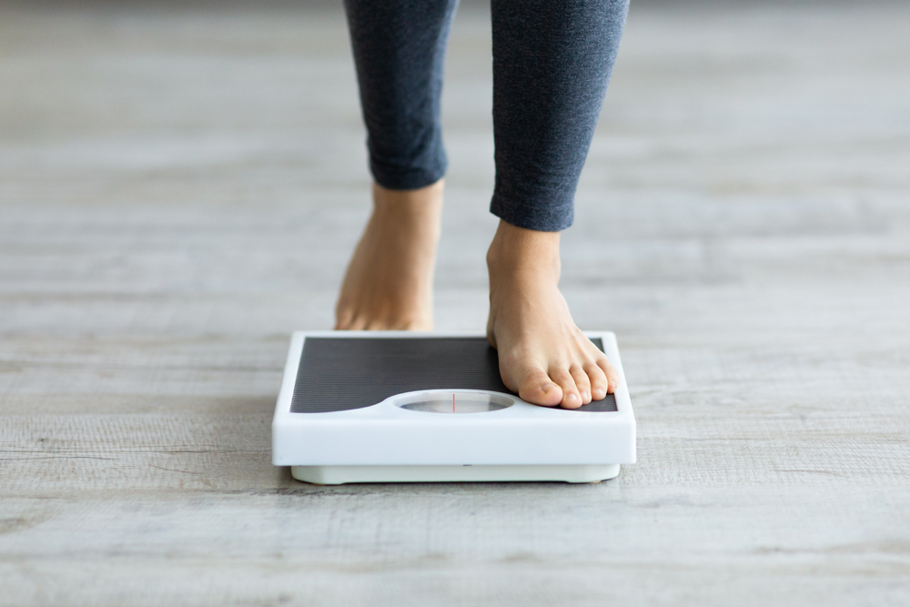 Unrecognizable young woman stepping on scales to measure her weight