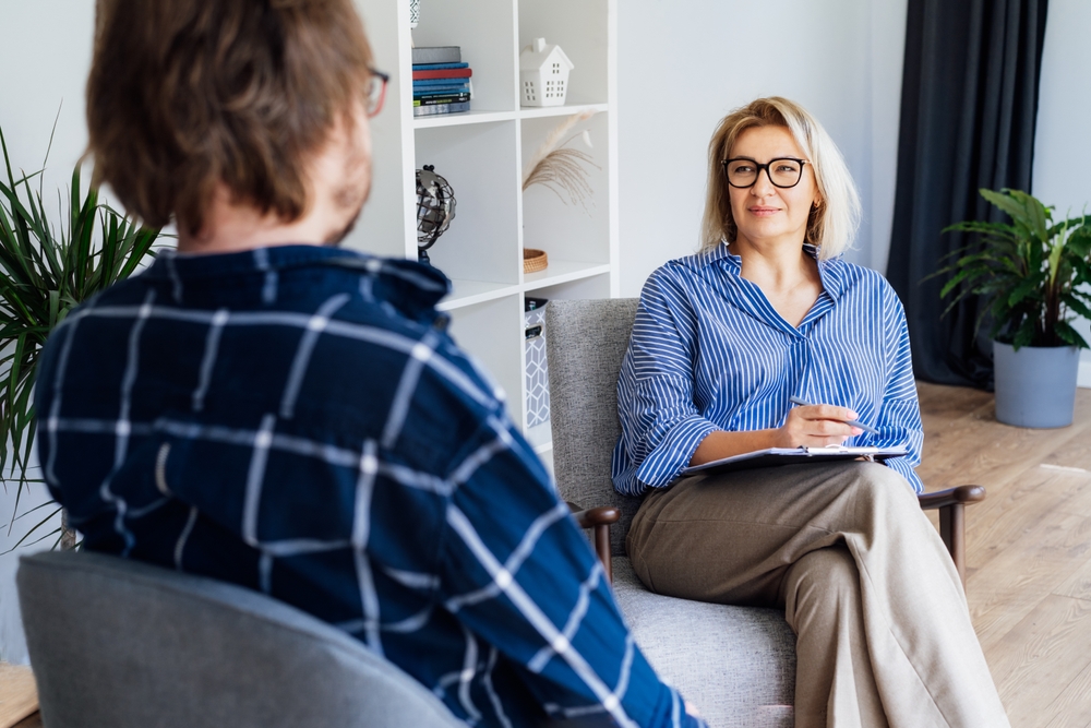Female psychiatrist having session with male patient at mental health clinic