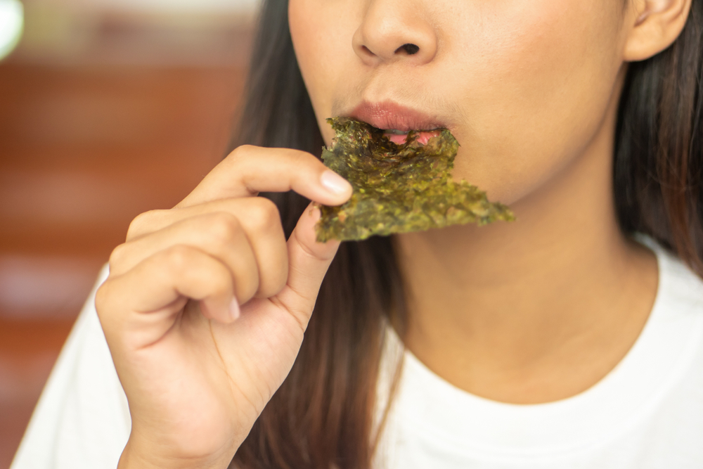 Woman eating dry seaweed.