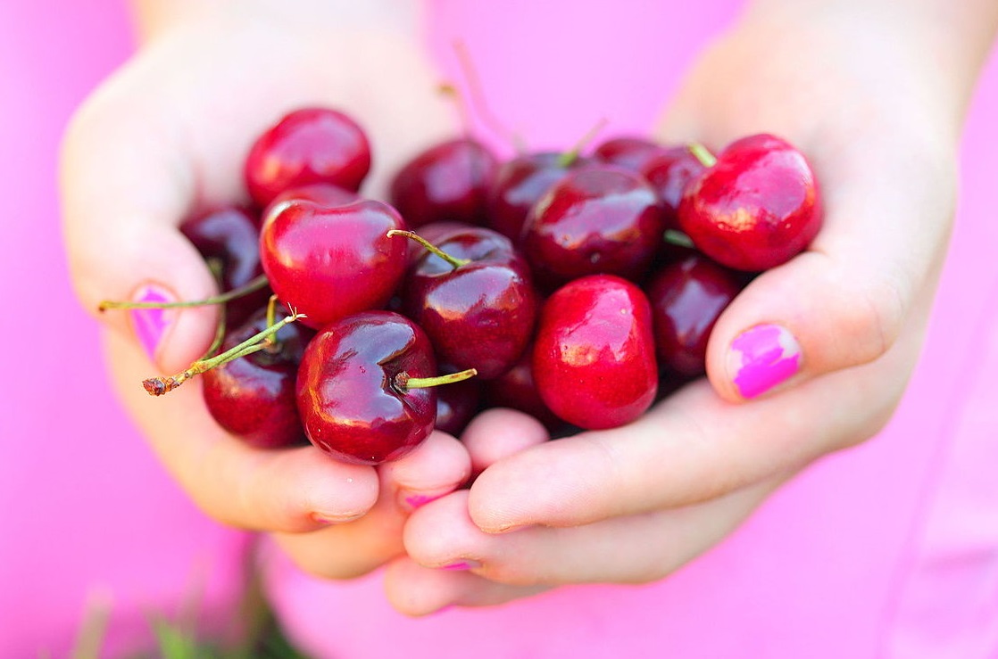 Woman holding cherries.