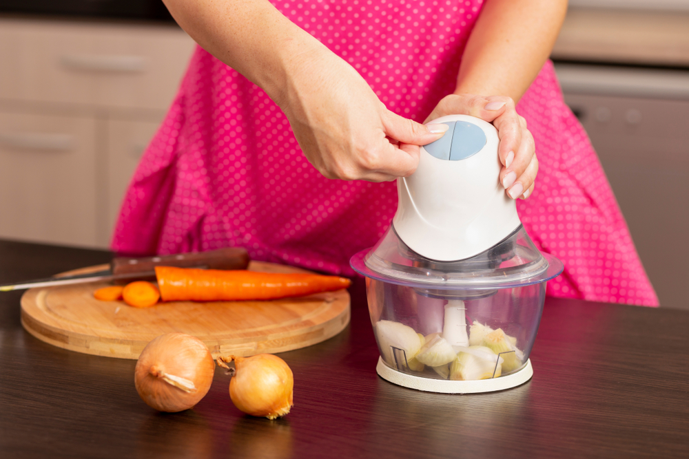Detail of female hands turning on an onion chopper on the kitchen counter