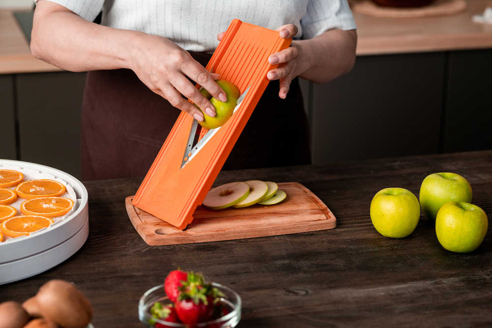 woman using mandoline slicer for cutting apple