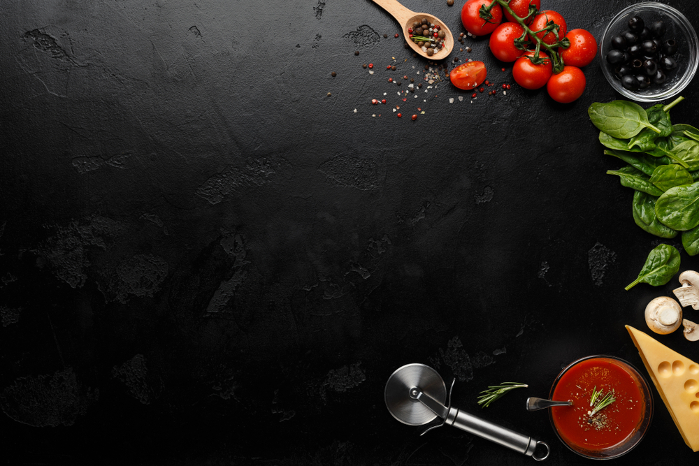 Pizza cutter and spices on black background