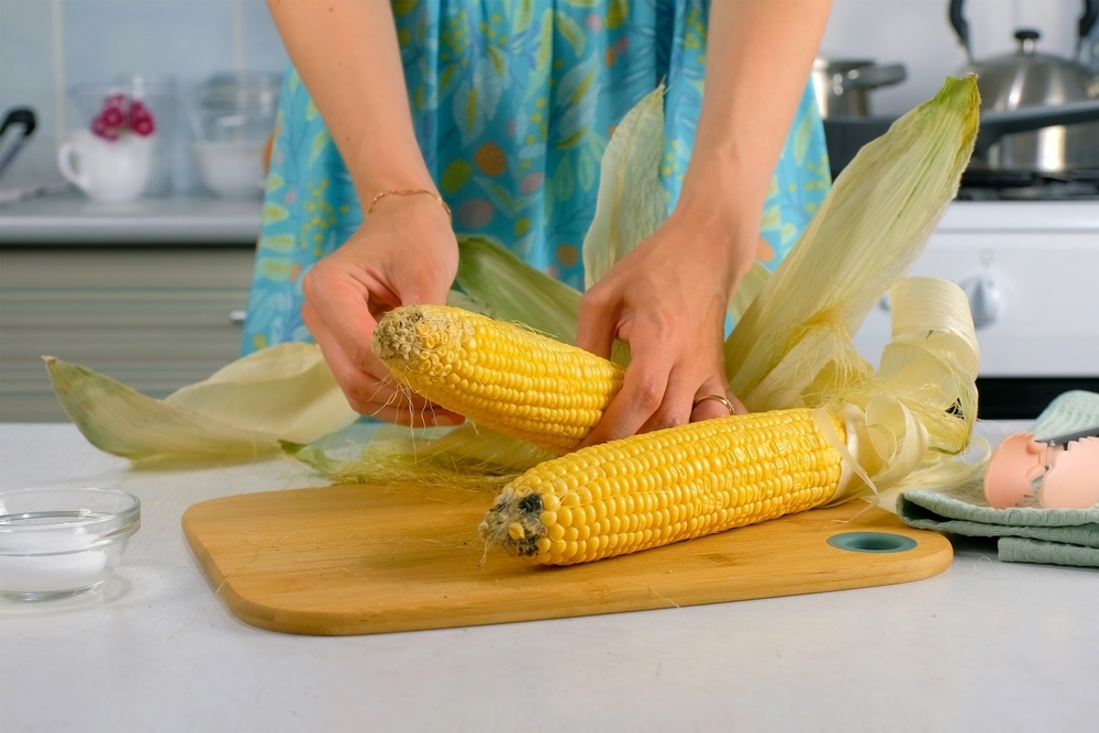 Woman peeling ears of corn