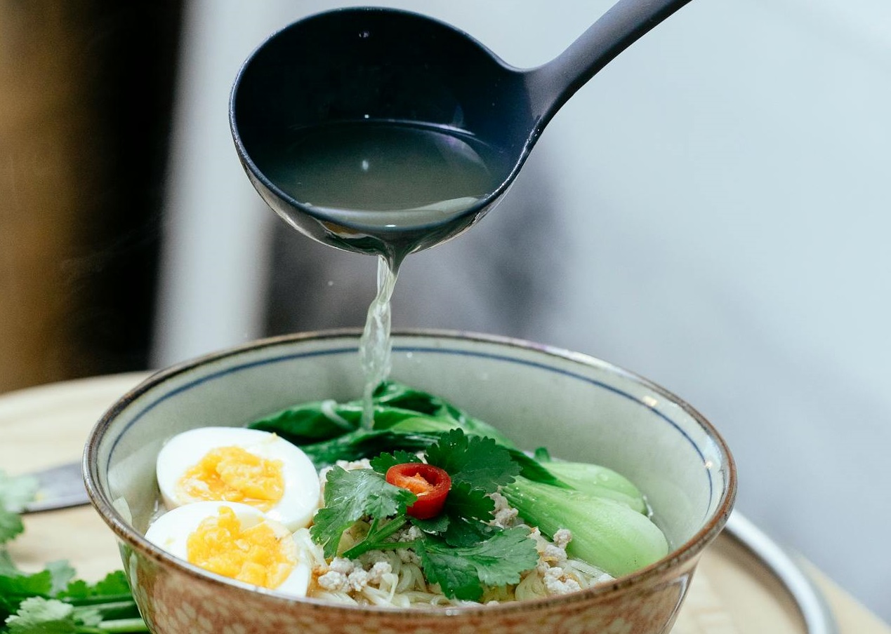 Pouring broth from ladle into bowl