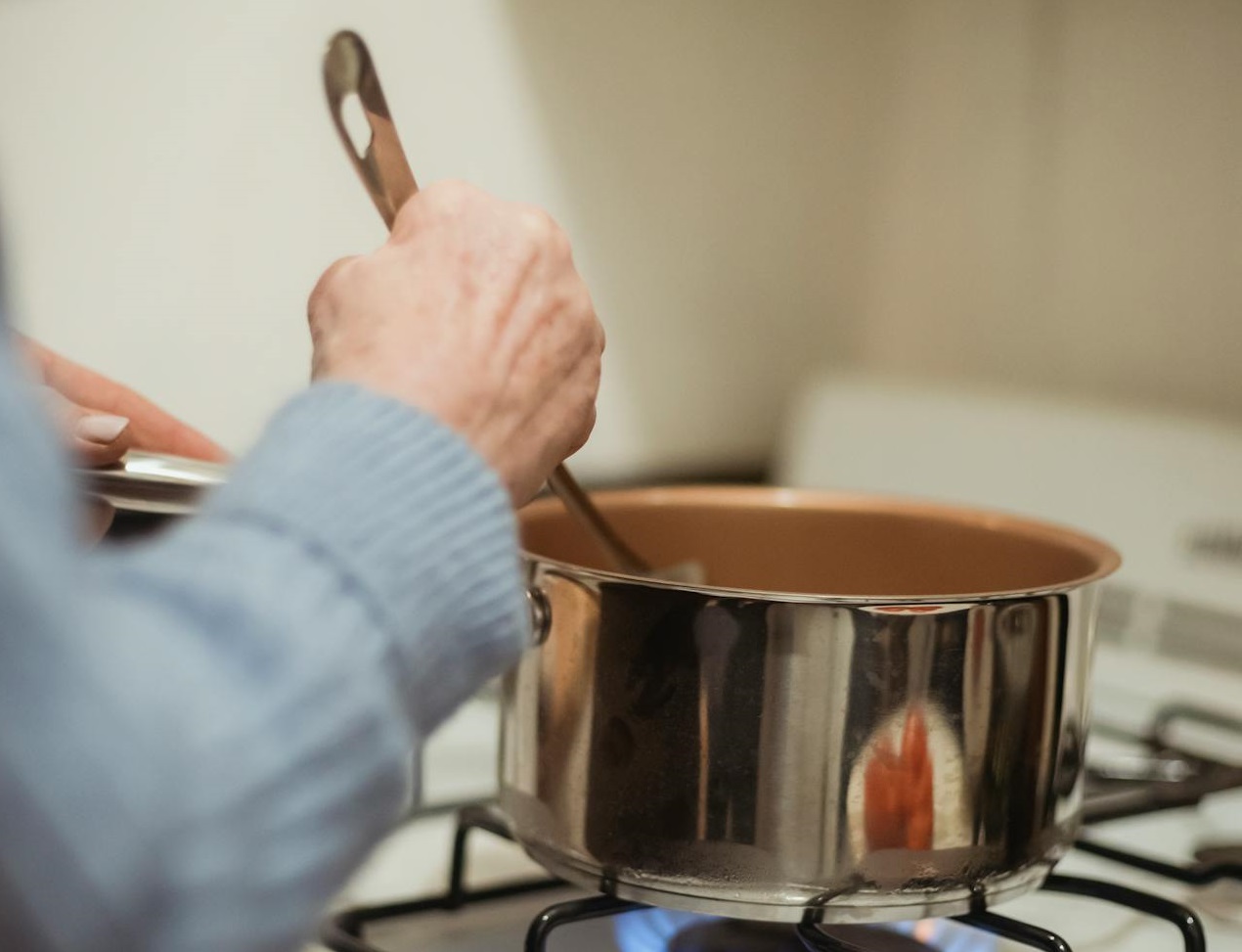 Crop unrecognizable housewife stirring boiling food in saucepan