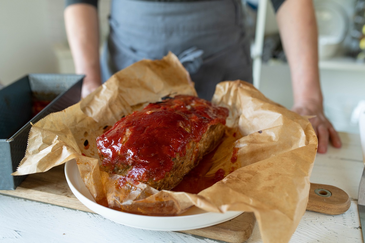 Fresh oven baked meatloaf with ketchup glaze with baking paper on kitchen counter
